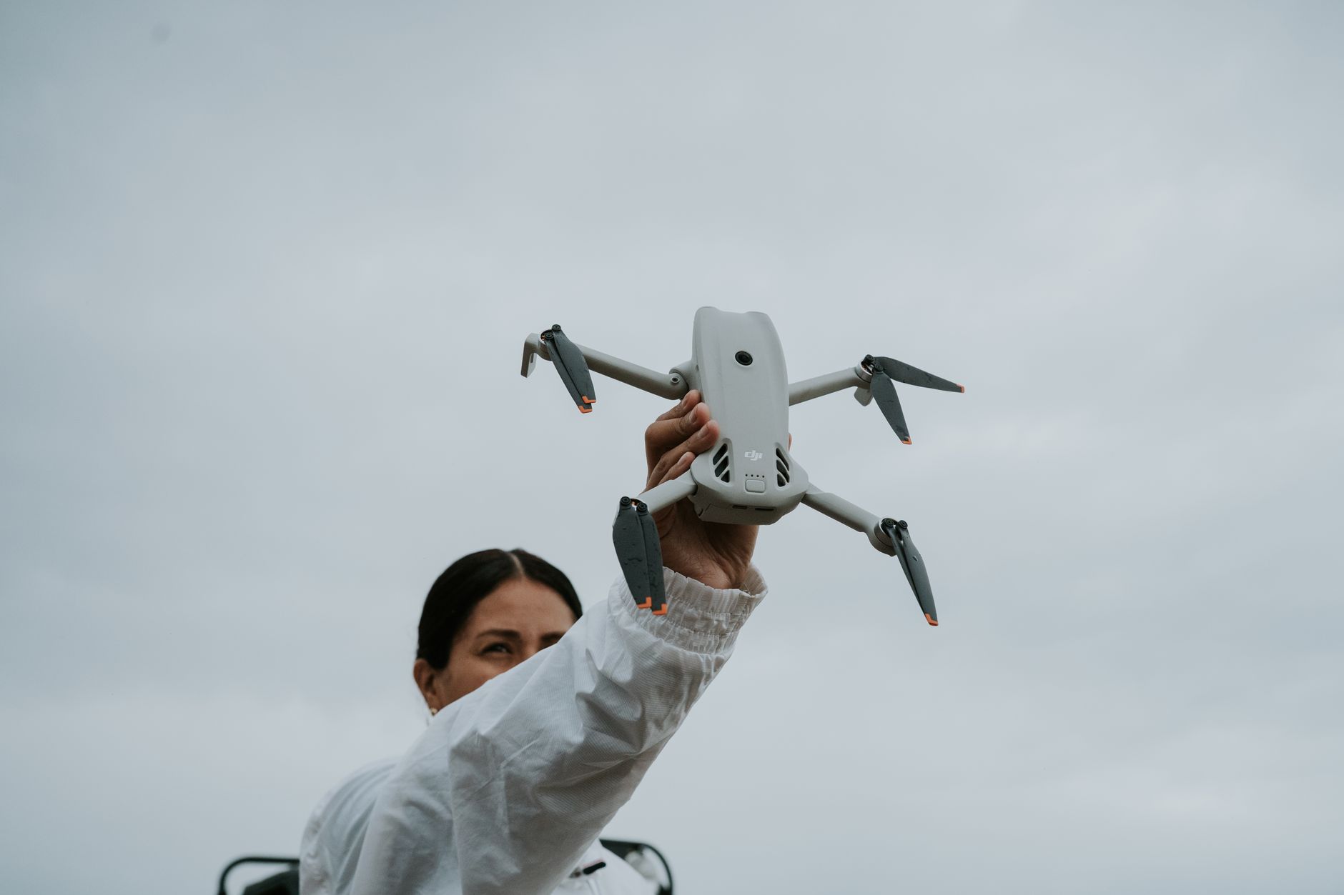 Person launching a small folding drone with propeller guards from an open field